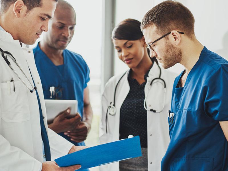 Several nurses standing together looking at a clipboard.